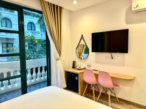 フーコックにあるChloe Marina Phu Quocのデスクとピンクの椅子2脚が備わるホテルルームです。