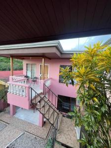 een roze huis met een balkon en een aantal bomen bij Departamento Ángeles del Arenal #2 in Fortuna