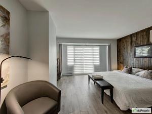 a bedroom with a bed and a chair and a window at Condo Phoenix prés du Lac Memphrémagog. in Magog-Orford