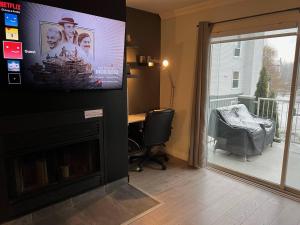 a living room with a flat screen tv above a fireplace at Condo Phoenix prés du Lac Memphrémagog. in Magog-Orford