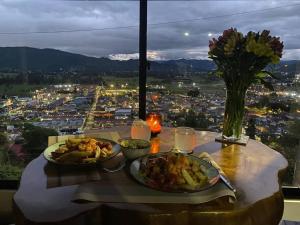 a table with two plates of food and a view of a city at Alojamiento/Lodging:El Indio Ese in Sopo