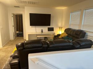 ein Wohnzimmer mit einem Ledersofa und einem Flachbild-TV in der Unterkunft Ebenezer in Glendale