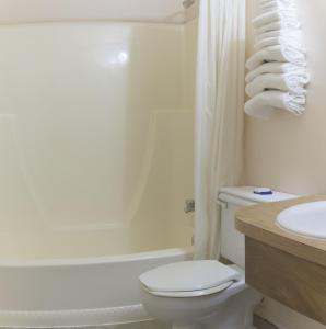 a bathroom with a toilet and a tub and a sink at Sun-Dek Motel in Medicine Hat