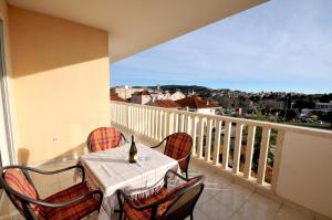 - une table avec des chaises et une bouteille de vin sur le balcon dans l'établissement Apartments and rooms with parking space Trogir - 22531, à Trogir