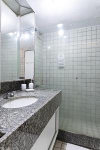 a bathroom with a sink and a mirror at Golden Beach Flat Recife in Recife