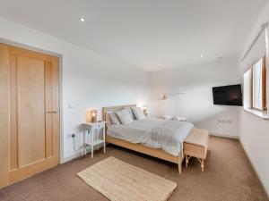 a white bedroom with a bed and a tv at The Beaches in Berwick-Upon-Tweed