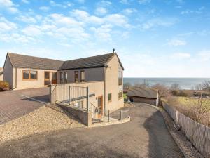 a house with a fence next to a road at The Beaches in Berwick-Upon-Tweed