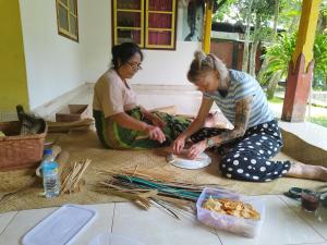 two women sitting on the floor with a plate of food at Bale Tetebatu in Tetebatu