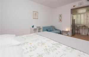 1 Schlafzimmer mit einem weißen Bett und einer floralen Tagesdecke in der Unterkunft Nice Apartment In Baska Voda With Kitchen in Baška Voda