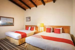 a bedroom with two beds with red and white at Hacienda Corteza in Rosarito