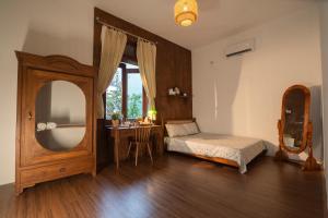 Schlafzimmer mit einem Bett, einem Spiegel und einem Tisch in der Unterkunft Hue Memories homestay 2 in Hue
