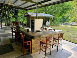 una cocina al aire libre con bar y sillas en Rugading Riverside Villa near Kota Kinabalu. en Kampong Rugarding