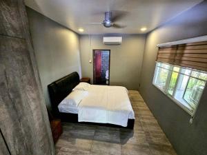 1 dormitorio con cama blanca y ventana en Rugading Riverside Villa near Kota Kinabalu. en Kampong Rugarding