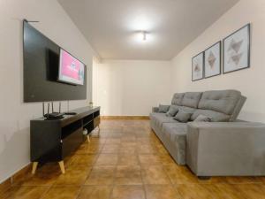 a living room with a couch and a flat screen tv at Apartamento Smart Centro MC53 in Maringá