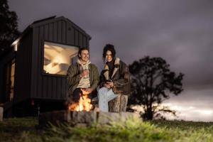 two men sitting next to a fire in front of a building at Tiny Nancy in Bellingen