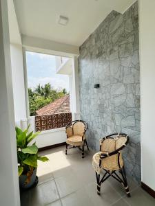 Un balcón con 2 sillas y una pared de piedra. en Matheera holiday home, en Jaffna