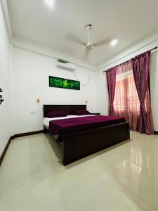 een slaapkamer met een groot bed met paarse lakens bij Matheera holiday home in Jaffna