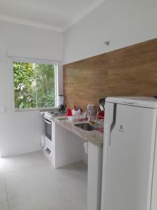 biała kuchnia ze zlewem i oknem w obiekcie Moriá Flats w mieście Ubatuba
