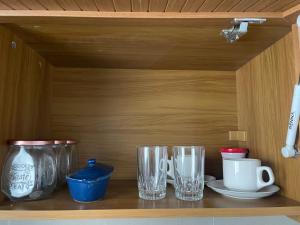 a wooden cabinet with glasses on a shelf at Casa BellsBeach 1 in Salvador