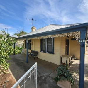 a small yellow house with a porch and a bench at Temoca Cottage Echuca Central in Echuca