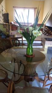 a vase with white flowers on a glass table at La Casona del Lago in Balneario Ipora