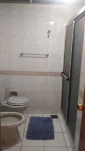 a bathroom with a toilet and a shower with a blue rug at La Casona del Lago in Balneario Ipora