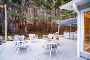 una terraza con sillas, mesas y una pérgola en Prattvilla -Catskill -Mountain Escape 5 BR ,3 bath with Hot tub en Prattsville