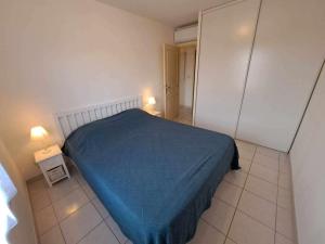 1 dormitorio con 1 cama con manta azul y 2 lámparas en Appartement Marseillan, 3 pièces, 4 personnes - FR-1-326-806, en Marseillan