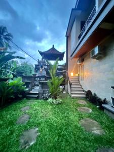 un patio trasero con césped verde y un edificio en Rare House en Ubud