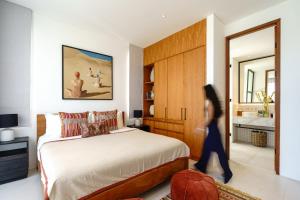 a woman walking through a bedroom with a bed at Mandala Residences in Canggu