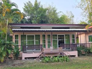 Cette maison rose dispose d'une terrasse couverte et d'un balcon. dans l'établissement ภูร์ชรินท์ รีสอร์ท, à Ban Than Phra