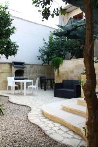 un patio con mesa, sillas y chimenea en Monterussi Bed and Breakfast, en Cavallino di Lecce
