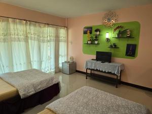 a bedroom with two beds and a table with a television at ภูร์ชรินท์ รีสอร์ท in Ban Than Phra