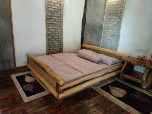 a wooden bed in a room with a table at Cahaya Wooden Studio in Pantai Cenang