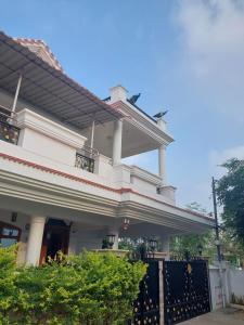 una casa blanca con una puerta negra en Shri Sai Baba Homestay - EB Colony - Trichy en Tiruchchirāppalli