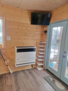 um quarto com uma parede de madeira com um aquecedor e uma televisão em Birch Tree Cabins em Homer