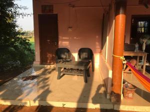 a patio with two chairs and a bench on a porch at Gokarna Ocean Tree in Gokarna