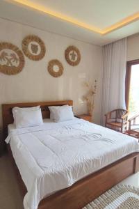 a bedroom with a bed with white sheets and pictures on the wall at Villa Maha IV in Dalung +15 photos