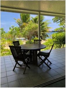 una mesa y sillas en un patio con vistas al océano en Les pieds dans l’eau à huahine. Maison climatisée, en Parea