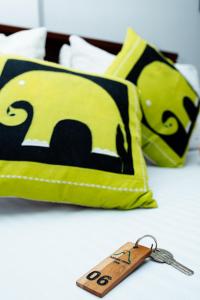 a remote control sitting next to two pillows at Adams Peak Inn in Adams Peak