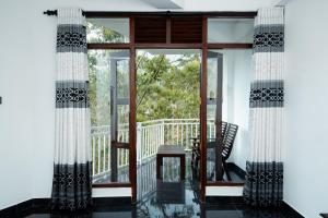 a room with a glass door and a chair on a balcony at Adams Peak Inn in Adams Peak