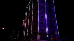 un edificio alto con luci viola sopra la notte di Hotel Hilen De Ville a Erbil