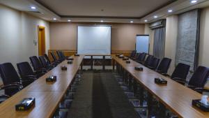 a conference room with desks and chairs and a whiteboard at Hotel Hilen De Ville in Erbil