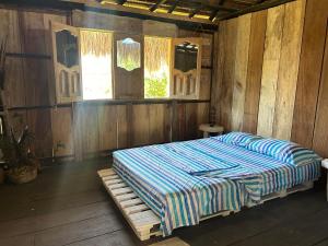 a bed in a room with wooden walls and windows at EcoHostal & EcoFit Punta Arena in Playa Punta Arena