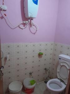 łazienka z toaletą i telewizorem na ścianie w obiekcie Ram priya kunj Atithi Niketan w mieście Ayodhya