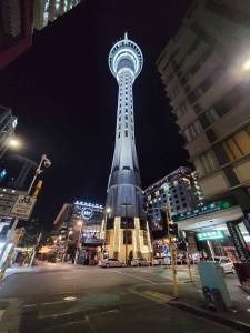 a tall tower in a city at night at Sky tower just next DOOR in Auckland