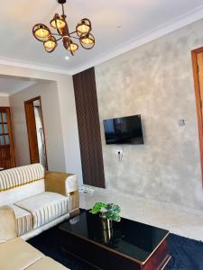 a living room with a couch and a tv at Vera's Luxury Home Near Speke Resort Munyonyo in Munyonyo