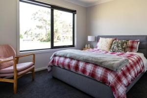 a bedroom with a bed and a chair and a window at 44onRoaring - in the Huon Valley in Surveyors Bay +104 photos