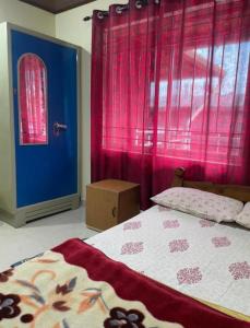 a bedroom with a bed with pink curtains and a blue door at Brindavan cottage in Madikeri