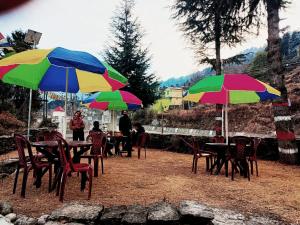 a group of tables and chairs with colorful umbrellas at Shangri-La Peaceful stays in Munsyari